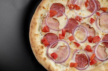 freshly made pizza close-up; details of the pizza application; juicy pizza from the oven with mushrooms, tomatoes and bacon and sprinkled with parmesan cheese