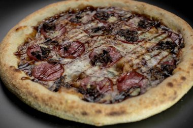 freshly made pizza close-up; details of the pizza application; juicy pizza from the oven with mushrooms, tomatoes and bacon and sprinkled with parmesan cheese