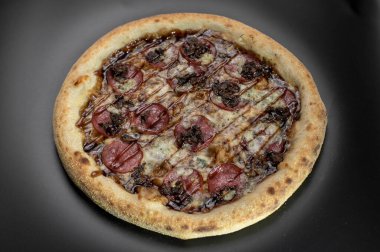 freshly made pizza close-up; details of the pizza application; juicy pizza from the oven with mushrooms, tomatoes and bacon and sprinkled with parmesan cheese