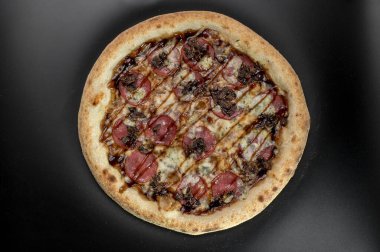 freshly made pizza close-up; details of the pizza application; juicy pizza from the oven with mushrooms, tomatoes and bacon and sprinkled with parmesan cheese