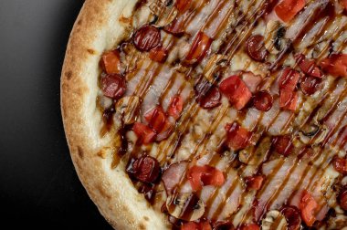 freshly made pizza close-up; details of the pizza application; juicy pizza from the oven with mushrooms, tomatoes and bacon and sprinkled with parmesan cheese