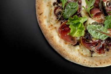 freshly made pizza close-up; details of the pizza application; juicy pizza from the oven with mushrooms, tomatoes and bacon and sprinkled with parmesan cheese