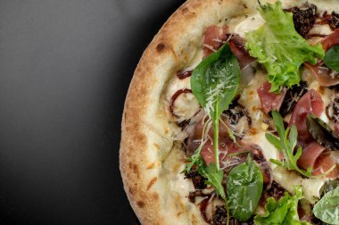 freshly made pizza close-up; details of the pizza application; juicy pizza from the oven with mushrooms, tomatoes and bacon and sprinkled with parmesan cheese