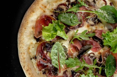 freshly made pizza close-up; details of the pizza application; juicy pizza from the oven with mushrooms, tomatoes and bacon and sprinkled with parmesan cheese