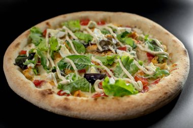 freshly made pizza close-up; details of the pizza application; juicy pizza from the oven with mushrooms, tomatoes and bacon and sprinkled with parmesan cheese