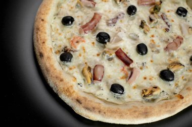 freshly made pizza close-up; details of the pizza application; juicy pizza from the oven with mushrooms, tomatoes and bacon and sprinkled with parmesan cheese