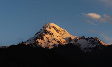 Gürcistan 'daki dağ zirvesi, güneş ışığıyla, siluet tepeleriyle.