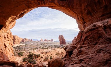 Arches National Park. A window look from inside of a huge cave at double arches hiking trail.  clipart