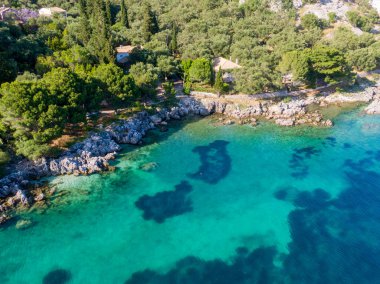 Turkuaz suların ve yemyeşil sularda yuva yapmış kıyı evlerinin havadan görünüşü.
