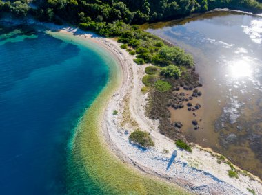 Turkuaz suları ve yemyeşil suları olan tenha bir sahil manzarası..