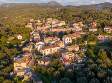 Bir vadide yuva yapmış, gün batımının sıcacık parıltısıyla yıkanmış tuhaf bir köyün havadan görünüşü..