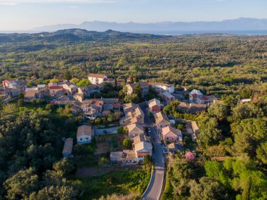 Yeşilliklerin ve yuvarlanan tepelerin arasında yuva yapmış tuhaf bir köyün havadan görünüşü..