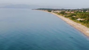 Kumlu sahili ve turkuaz suyu olan bir sahil kasabasının havadan görünüşü..