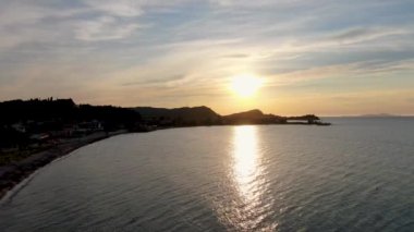 Sakin bir kasabanın üzerinde kıyı günbatımı. Suyun üzerinde parıldayan yansımalarla..