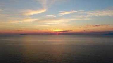 Uzak ada siluetiyle sakin bir okyanusun üzerinde nefes kesici bir gün batımı..