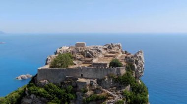 Angelokastro 'nun nefes kesen hava manzarası, Yunanistan' ın Korfu adasındaki bir uçurumun tepesine tünemiş bir Bizans kalesi. Harabeler, canlı mavi deniz ve yeşil manzaranın tam zıttı.,