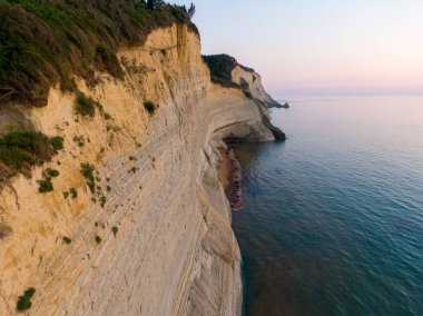 Dramatik uçurumlar gün batımında dingin bir okyanusla buluşur.