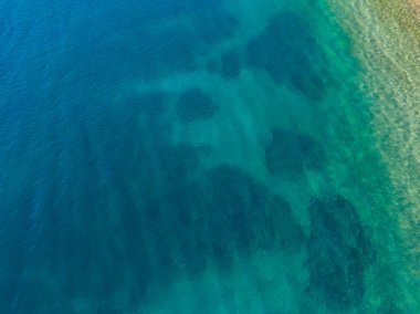 Kristal berraklığında turkuaz suyun havadan görünüşü.