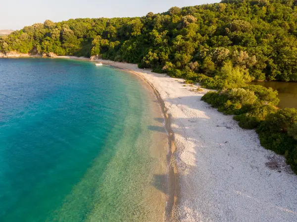 Sakin beyaz kumsal turkuaz suyla birleşir. yemyeşil orman arkaplanı.
