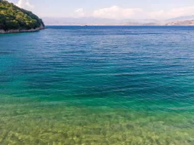 Kristal berrak su ve yemyeşil kıyı şeridiyle sakin turkuaz koy..