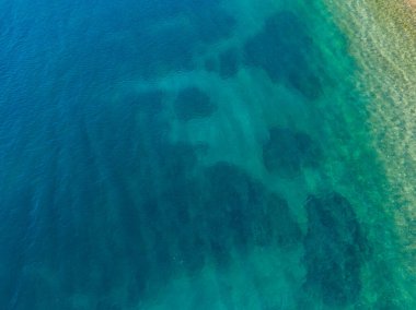 Kristal berraklığında turkuaz suyun havadan görünüşü.