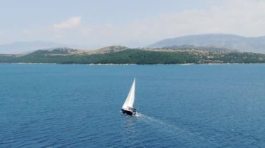 Mavi sularda yüzen yelkenli arkasında küçük bir sandal, Korfu, Yunanistan