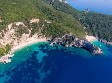 Uçsuz bucaksız mavi okyanusla yemyeşil tepeler arasında uzanan tenha plajların havadan görünüşü..