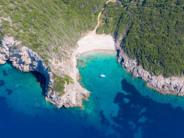 Turkuaz suyu ve teknesi olan tenha bir sahil manzarası..