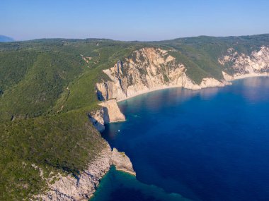Uçurumlar ve yemyeşil yeşillikler arasında yuva yapmış, güneş ışığıyla yıkanmış tenha bir sahil manzarası..