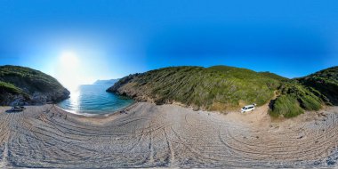 Tenha sahil koyunda turkuaz su ve parlak güneşin altında yeşil tepeler..