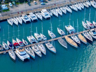 Güneşli bir günde yelkenli tekneler ve yatlarla dolu marina manzarası..