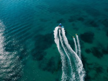 Canlı bir okyanusu geçen iki yumruyu çeken bir teknenin havadan görünüşü. Kristal berrak su ve güneşli gün.