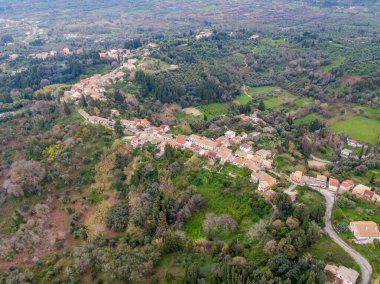 Yeşil bir arazide yuva yapmış büyüleyici bir köyün havadan görünüşü. Yeşilliklerle çevrili, tepelere yapışmış evler..