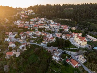 Gün batımında tepedeki köyde renkli evler ve bir kilise sergileniyor..