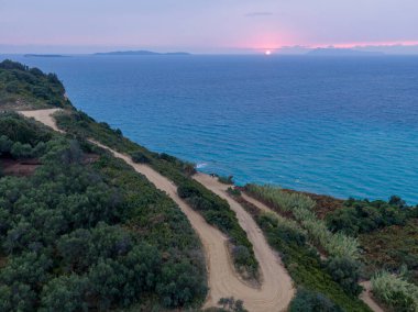 Sahil manzarası, sakin okyanusa bakan yuvarlak toprak yol. Huzurlu manzara fotoğrafçılığı.