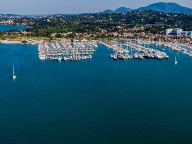Resimli bir sahil şeridine kurulmuş tekne ve yatlarla dolu bir marinanın havadan görüntüsü..