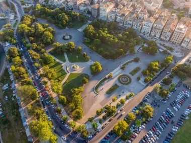 Şehir parkının ve caddelerin hava manzarası yemyeşil ve park edilmiş arabaları gösteriyor..