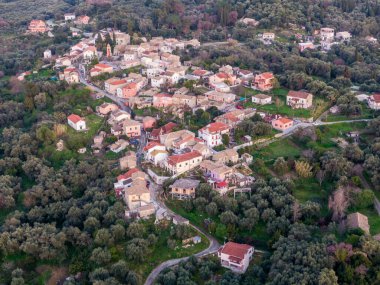 Yeşillik ve yemyeşil bir arazide yuva yapmış büyüleyici bir köyün havadan görünüşü. Kırmızı kiremit çatılı geleneksel evler etrafa saçıldı..