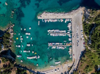 Canlı turkuaz bir koyda yuva yapmış, teknelerle dolu bir marinanın havadan görüntüsü..