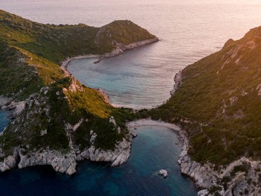 Tenha bir koy, turkuaz sular, dramatik uçurumlar. Gizli bir sahil havadan gün batımı görüntüsü.