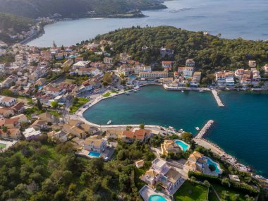 Sahil kasabası, yemyeşil yemyeşil ve ışıl ışıl mavi sularla çevrili sakin bir körfeze kurulmuş. Resimli bir hava manzarası.