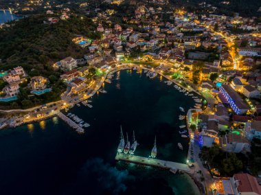 Bir sahil kenti limanının gece manzarası. Tekneleri ve aydınlık binaları var..