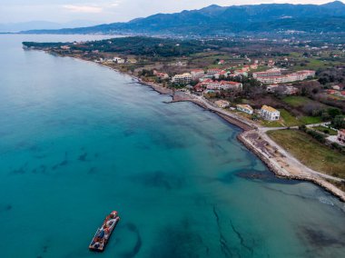 Bir sahil kasabasının havadan görünüşü, turkuaz su ve küçük bir gemi..