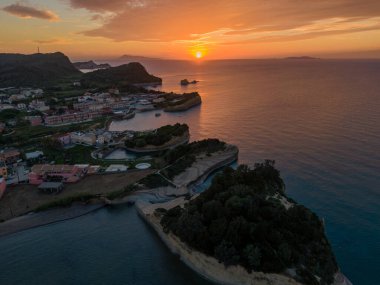 Sahil kasabasında ve okyanusta gün batımı. Dramatik gökyüzü renkleri sahneyi boyuyor.