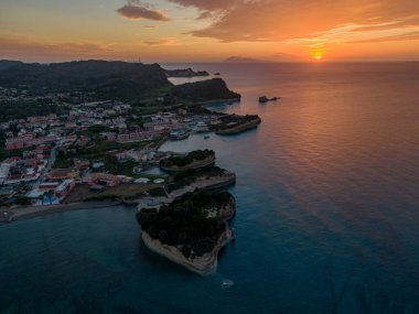 Sahil kasabasında gün batımı ve dramatik uçurumlar. Altın saatinde okyanusun, binaların ve kaya oluşumlarının göz kamaştırıcı hava manzarası.