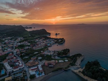 Sahil kasabasının günbatımı hava manzarası. Altın saat renkleri gökyüzünü resim gibi bir sahil köyüne boyuyor..