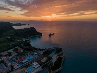 Huzurlu bir körfezin üzerinde sahil gün batımı. Tatil evleri ve dramatik uçurumlar..