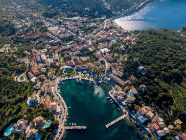 Sakin bir körfezin yanındaki kıyı kasabasının havadan görünüşü. Açık mavi suları çevreleyen binalar ve yemyeşil alanlar.