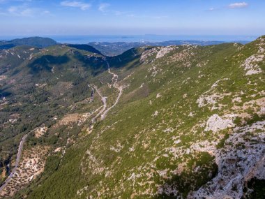Dönek yolu ve uzak denizi olan sakin dağ manzarası.