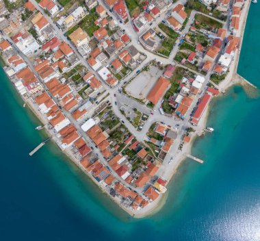 Sahil kasabasının hava manzarası. Kırmızı çatılı evler rıhtım boyunca uzanır. Resimli bir sahne sunar..